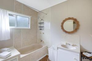 a bathroom with a tub and a sink and a mirror at Betty's Place in Amity Point