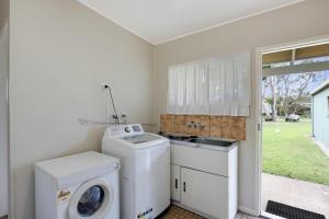 a laundry room with a washing machine and a sink at Betty's Place in Amity Point