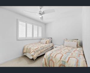 a bedroom with two beds and a ceiling fan at Walk to Beach • Luxury Waterfront Penthouse in Mooloolaba +14 photos