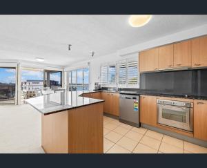 a large kitchen with wooden cabinets and black counter tops at Walk to Beach • Luxury Waterfront Penthouse in Mooloolaba