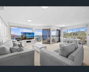 a living room with two couches and a flat screen tv at Walk to Beach • Luxury Waterfront Penthouse in Mooloolaba