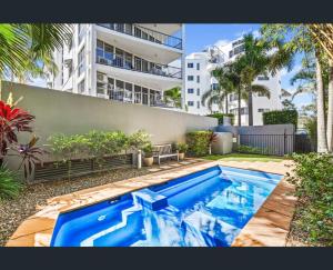 a blue swimming pool in front of a building at Walk to Beach • Luxury Waterfront Penthouse in Mooloolaba
