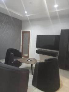 a room with chairs and a table and a tv at Triple 9 Apartments,Pool & Spa in Abuja