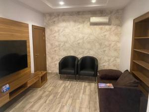 a living room with two chairs and a flat screen tv at Triple 9 Apartments,Pool & Spa in Abuja