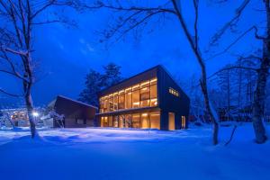 a black building in the snow at night at JADE Amber Resort Hakuba in Hakuba