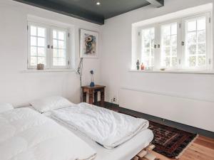 a white bedroom with a bed and two windows at Home with Spa and Fireplace in Fanø