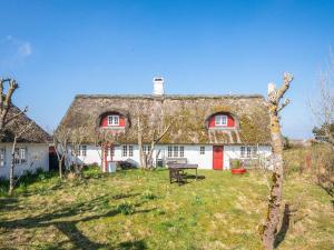 a house with a thatched roof with a picnic table at Home with Spa and Fireplace in Fanø