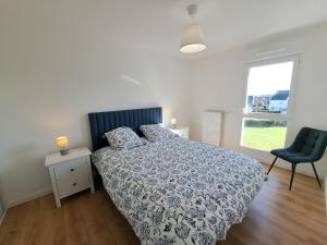 a bedroom with a bed and a chair and a window at Sea View Family Stay in Plouarzel in Plouarzel