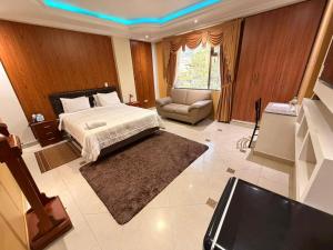 a bedroom with a bed and a couch and a tv at Hotel Troya in Ibarra