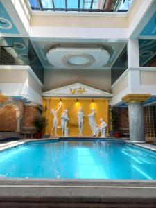 a swimming pool in a building with a painting on the wall at Hotel Troya in Ibarra