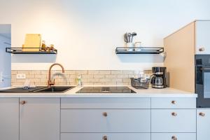 a kitchen with white cabinets and a sink at Cottage am Deich Whg Marlene in Uelvesbüll +26 photos