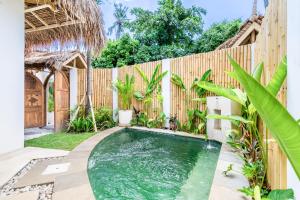 a swimming pool in a backyard with a wooden fence at Villa Anak Ikan in Gili Islands
