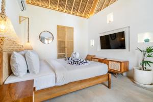 a bedroom with a bed and a television in it at Villa Anak Ikan in Gili Islands
