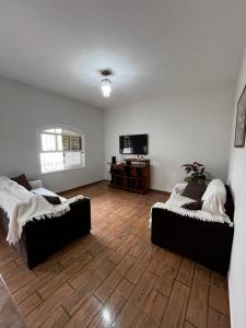 a living room with two beds and a flat screen tv at Casa Vitória in Aparecida