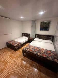 a room with two beds in a room with a floor at Hotel Confortel in Armenia