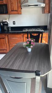 a table in a kitchen with a vase of flowers on it at casa Borde Del Lago1 in Panajachel