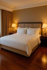a bedroom with a large white bed with two lamps at Oscar Apartments in Cairo +3 photos