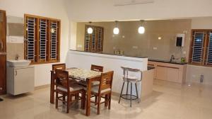 a kitchen with a table and chairs in a room at Santhosh Villa in Thanjāvūr