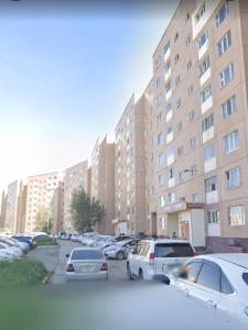 a parking lot with cars parked in front of tall buildings at Cozy 2 BR Apartment with Easy Access in Ulaanbaatar