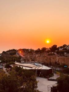 a sunset over a parking lot with the sun setting at Venus sea view in Paphos