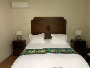 a bedroom with a bed with two nightstands and two lamps at Hacienda Escondida 10min to Airport in Alajuela