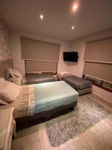 a bedroom with three beds and a flat screen tv at Lib Hotel Bellavista in Santiago