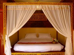 a bed with a canopy with white curtains at Irawadee Resort in Mae Sot
