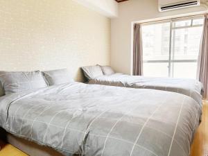 two beds in a bedroom with a window at Crest YS chiyoda 4B in Aoichō +12 photos