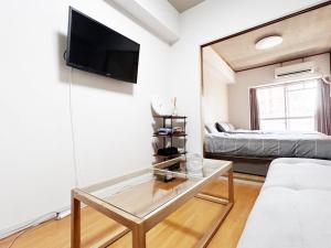 a living room with a couch and a tv on a wall at Crest YS chiyoda 4B in Aoichō