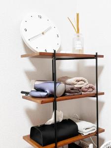 a clock on a wall next to a shelf with towels at Crest YS chiyoda 4B in Aoichō