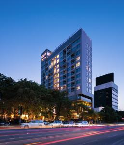 a tall building with cars parked in front of a street at One Residence Hotel & Apartment in Phnom Penh