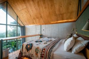 a bedroom with a bed with a wooden ceiling at Black Wood Cabin in Kintamani