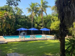 a swimming pool with blue umbrellas and a pool at Pousada Ypê Amarelo in Itatiaia