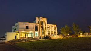 a large white building at night with its lights on at Raja Krishna Mahal in Kushinagar