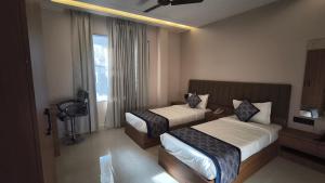 a hotel room with two beds and a window at Raja Krishna Mahal in Kushinagar
