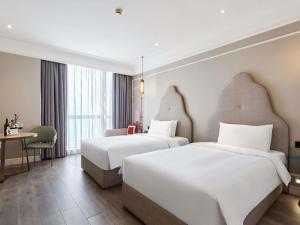 a hotel room with two beds and a desk at Mercure Beijing City Center in Beijing