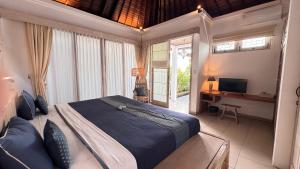 a bedroom with a bed and a desk and a television at Artemis Villa Hotel in Seminyak
