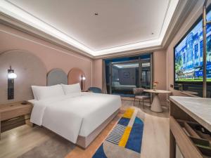a bedroom with a large white bed and a large window at Mercure Changbai Mountain North in Antu