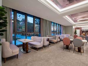 a waiting room with tables and chairs and windows at Mercure KunMing Airport in Kunming