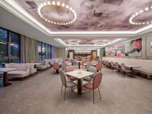 a restaurant with tables and chairs in a room at Mercure KunMing Airport in Kunming