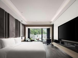 a bedroom with a large bed and a flat screen tv at Mercure Guilin Yangshuo Xingping in Guilin