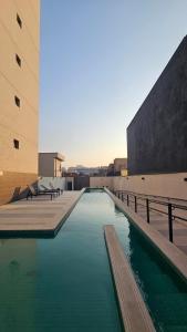 a pool of green water next to two buildings at Studio Aurora, Bom Retiro - Anhembi - Com garagem in São Paulo