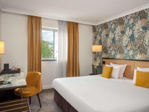a hotel room with a bed and a desk and a window at Hôtel Mercure Paris Boulogne Pont de Saint Cloud in Boulogne-Billancourt +74 photos