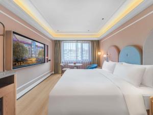 a hotel room with a large bed and a tv at Mercure Qingdao May Fourth Square in Qingdao