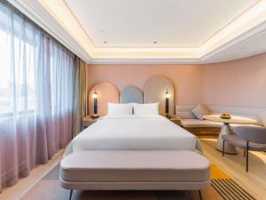 a bedroom with a bed and a large window at Mercure Qingdao May Fourth Square in Qingdao +86 photos