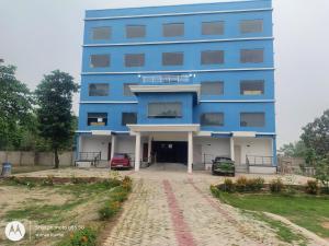 a blue building with two cars parked in front of it at Chouhan Resort in Katihār