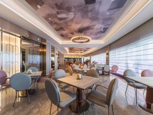 a restaurant with tables and chairs in a room at Mercure Qingdao Coast in Qingdao