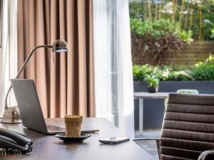 a desk with a laptop and a cup of coffee on it at Mercure Sydney St Leonards in Sydney