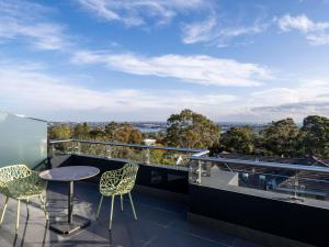 a balcony with a table and chairs on a roof at Mercure Sydney St Leonards in Sydney