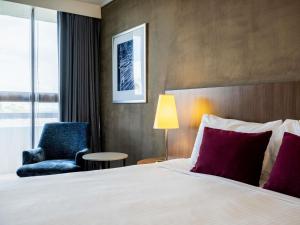 a hotel room with a bed and a chair at Mercure Sydney St Leonards in Sydney